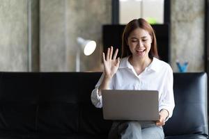 una joven asiática tiene un chat de video con amigos con cámara web, una joven empresaria asiática feliz saludando a su pareja durante una videoconferencia con su equipo.