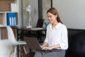 Portrait of confident businesswoman at workplace, smiling woman employee sitting behind laptop. photo
