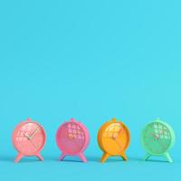 Four colorful retro alarm clocks on bright blue background in pastel colors. Minimalism concept photo