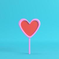 Pink with red heart on a stick on bright blue background photo