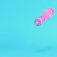 Pink syringe with vaccine on bright blue background in pastel colors photo