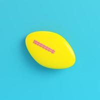 Yellow american football ball on bright blue background in pastel colors photo