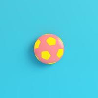 Yellow soccer ball on bright blue background in pastel colors photo