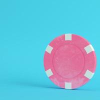 Pink casino chip on bright blue background in pastel colors photo
