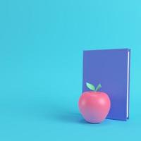 Pink apple and book on bright blue background in pastel colors photo