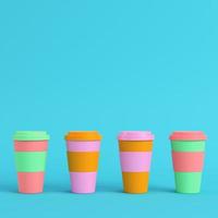 Four colorful coffee cups on bright blue background in pastel colors. Minimalism concept photo