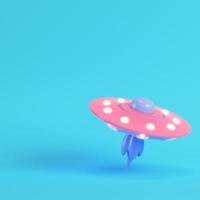 Pink ufo or alien spaceship on bright blue background in pastel colors photo