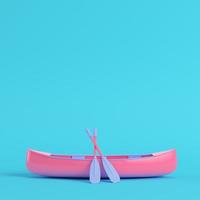 Pink canoe with paddles on bright blue background in pastel colors photo