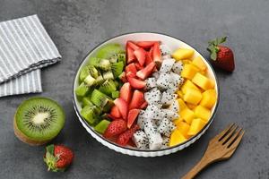 tazón de ensalada de fruta fresca saludable, fruta de dragón, kiwi, mango, fresa, sobre la mesa. imagen de enfoque seleccionada. foto