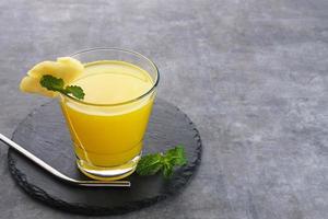 A glass of fresh pineapple juice with mint leaf and slice fruit. Cold Pressed Juice photo
