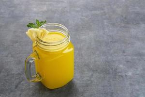 A glass of fresh pineapple juice with mint leaf and slice fruit. Cold Pressed Juice photo