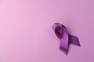 cinta morada como símbolo del día mundial del cáncer sobre fondo de color morado, espacio de copia. foto