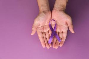 cinta morada como símbolo del día mundial del cáncer sobre fondo de color morado, espacio de copia. foto