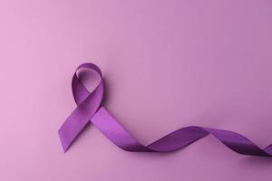 cinta morada como símbolo del día mundial del cáncer sobre fondo de color morado, espacio de copia. foto