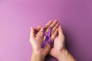 cinta morada como símbolo del día mundial del cáncer sobre fondo de color morado, espacio de copia. foto
