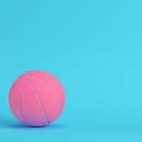 pelota de baloncesto rosa sobre fondo azul brillante en colores pastel. concepto de minimalismo foto