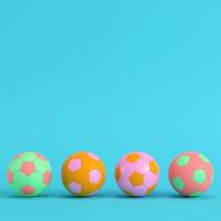 Four colorful soccer balls on bright blue background in pastel colors photo