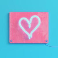 Pink plate with neon light heart shape on bright blue background in pastel colors photo