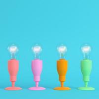 Four colorful lamps with glowing light bulb on bright blue background in pastel colors photo