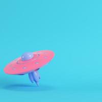 Pink ufo or alien spaceship on bright blue background in pastel colors photo