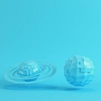 Two blue low poly planets on bright blue background in pastel colors photo