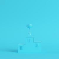 Pedestal with trophy cup on bright blue background in pastel colors. Minimalism concept photo