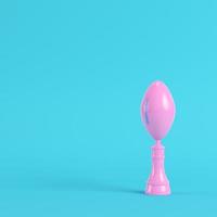 American football ball throphy on bright blue background in pastel colors. Minimalism concept photo