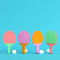 Four ping pong rackets with balls on bright blue background in pastel colors. Minimalism concept photo