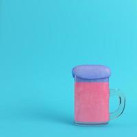 Mug of pink beer with blue foam on bright blue background in pastel colors photo