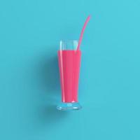 Glass with pink cocktail on bright blue background in pastel colors photo