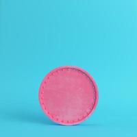 Pink blank scratched coin on bright blue background in pastel colors photo
