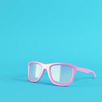 Pink sun glasses on bright blue background in pastel colors photo