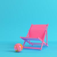 Pink beach chair with volleyball ball on bright blue background in pastel colors photo