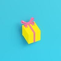 Yellow gift box with ribbon bow and on bright blue background in pastel colors photo