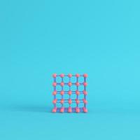 Abstract pink spheres in wire box on bright blue background in pastel colors photo