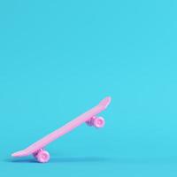 Pink low poly skateboard deck on bright blue background in pastel colors photo