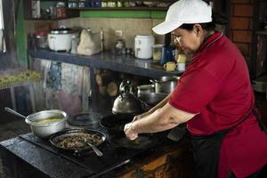 mujer de perfil concentrándose en cocinar en una estufa de leña. foto