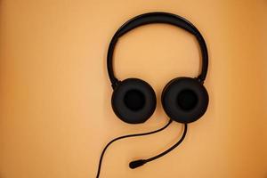 Modern Black Headphones isolated on orange background. photo