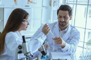 trabajador médico científico atractivo con tubo de ensayo de muestra en el laboratorio, haciendo un análisis en un laboratorio investigando para crear una vacuna y desarrollo foto