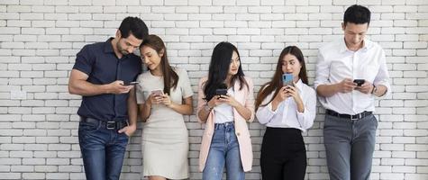 retrato de un grupo de amigos que usan teléfonos inteligentes y aplicaciones populares adictos a las nuevas tendencias tecnológicas, la tecnología y el concepto social de Internet foto