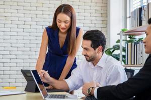 hombre de negocios que usa una tableta digital moderna mientras un compañero de trabajo interactúa en segundo plano en la oficina, reunión de trabajo en equipo y concepto de asociación. foto