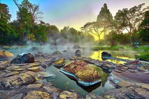 baño natural de aguas termales onsen en el parque nacional chae son, lampang tailandia. en el amanecer de la mañana. baño de aguas termales natural rodeado de montañas en el norte de tailandia. enfoque suave. foto