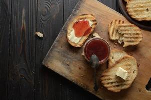 Toast bread with homemade strawberry jam and on rustic table with butter for breakfast or brunch.