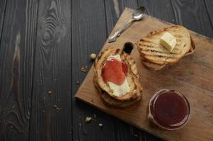 Toast bread with homemade strawberry jam and on rustic table with butter for breakfast or brunch.