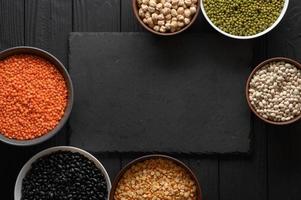 Legumes, overhead flat lay shot on a dark rustic wooden background with a place for text photo