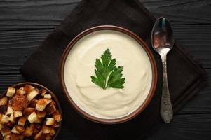 Cream of cauliflower soup on a dark wooden background. photo
