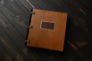 An old photo album with a wooden cover and a shield on a rustic table. free logo