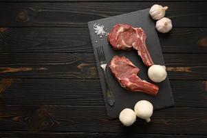 Raw cowboy steak and spices on a black wooden background. photo