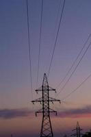 Close up high voltage power lines station. High voltage electric transmission pylon silhouetted tower. photo