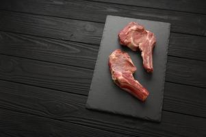 Raw cowboy steak and spices on a black wooden background. photo